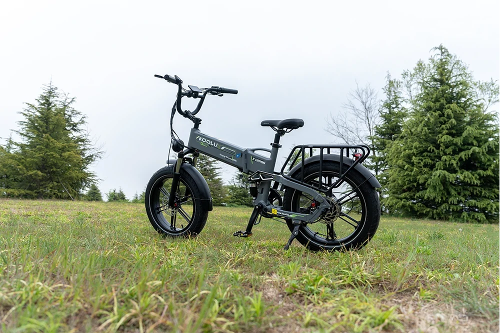 Grey KOOLU RK10 foldable fat tire electric bicycle standing on green grass, outdoor park background, leisure travel ebike