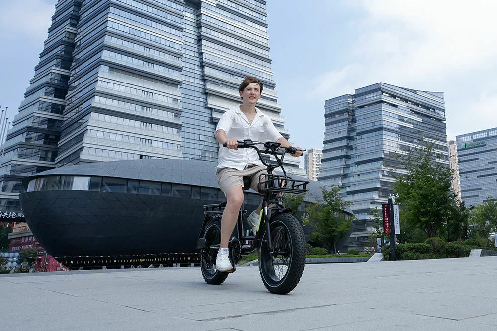 KOOLUX electric bike with front basket being ridden by man in front of modern glass CBD skyscrapers