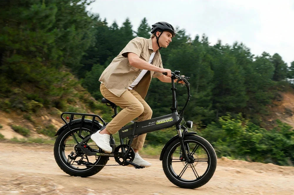 Male rider with helmet riding foldable fat tire electric bike on rough mountain dirt road, off‑road e‑bike for outdoor adventure and countryside travel
